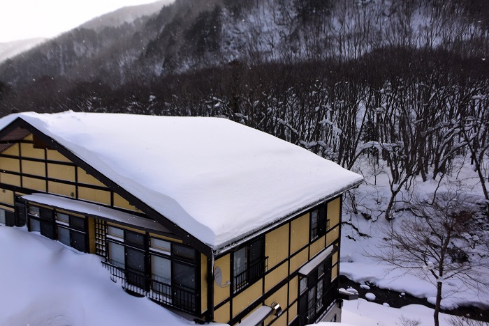 旧家の屋根の雪下ろしにて、檜枝岐川方面を望んで（２０２５年１月１８日）。